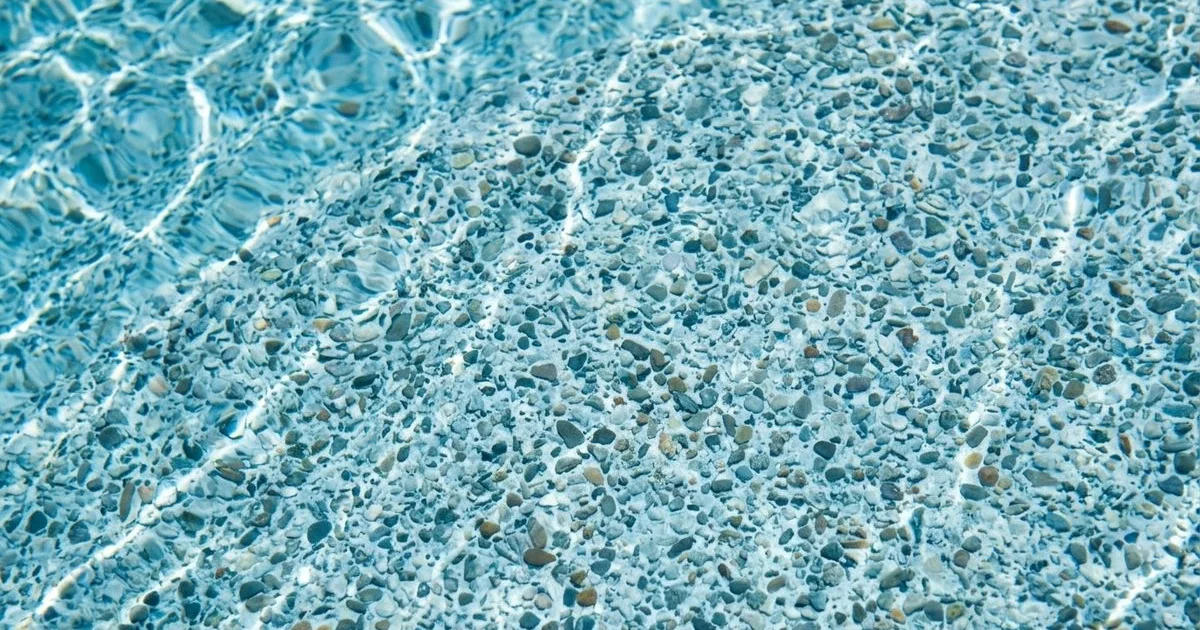 Close-up of blue Pebble Tec pool finish with sun-dappled water in an authentic Phoenix backyard